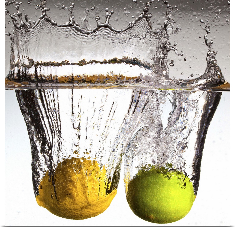 Square canvas photo of a lime and lemon moving through water with water splashing up at the top.