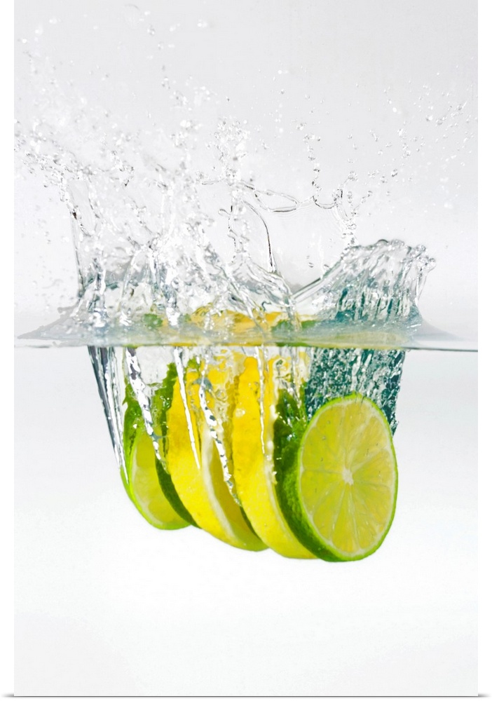 Huge photograph displays four slices of fruit as they splash into water.