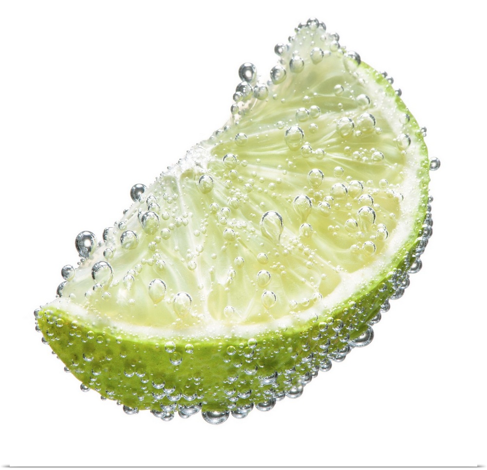 A juicy ripe organic lime wedge fruit submerged in clean clear refreshing water and covered in bubbles on a white backgrou...