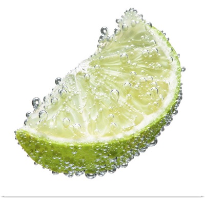 Lime wedge fruit submerged in  water and covered in bubbles