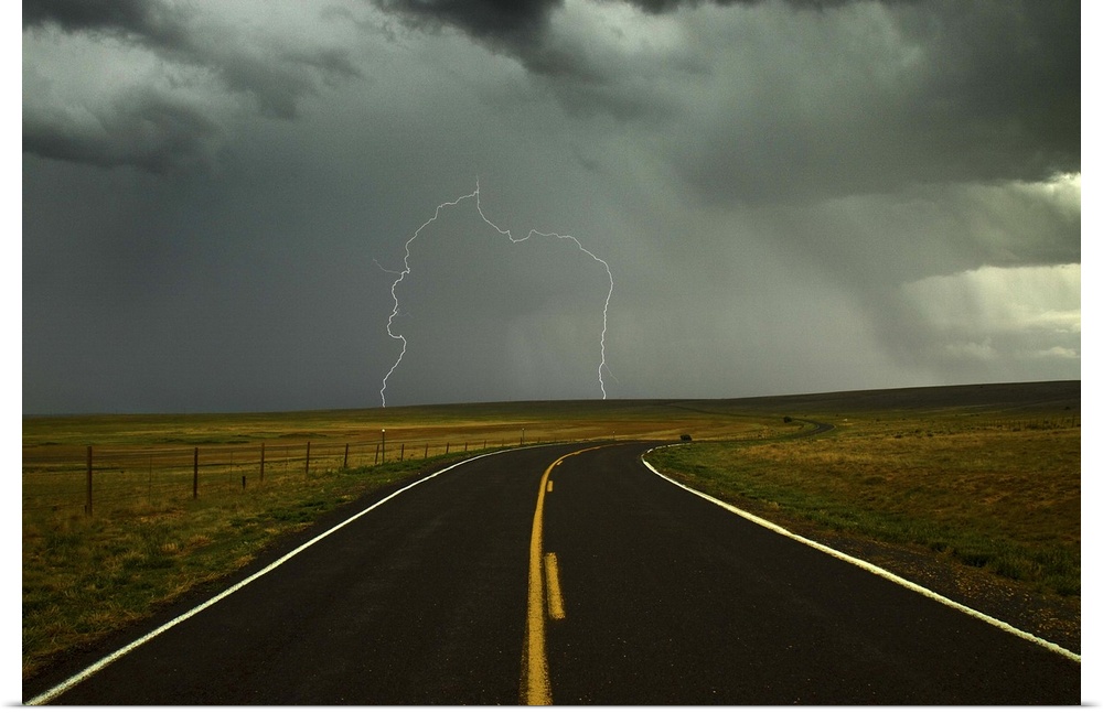Long and winding road against lighting strike in sky in Santa Fe Trail, Watrous, New Mexico.