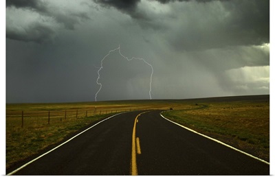 Long and winding road against lighting strike in sky in Santa Fe Trail, New Mexico.
