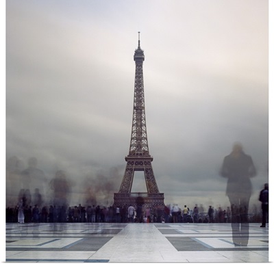 Long exposure of Eiffel Tower with figures in crowds blur in Paris.