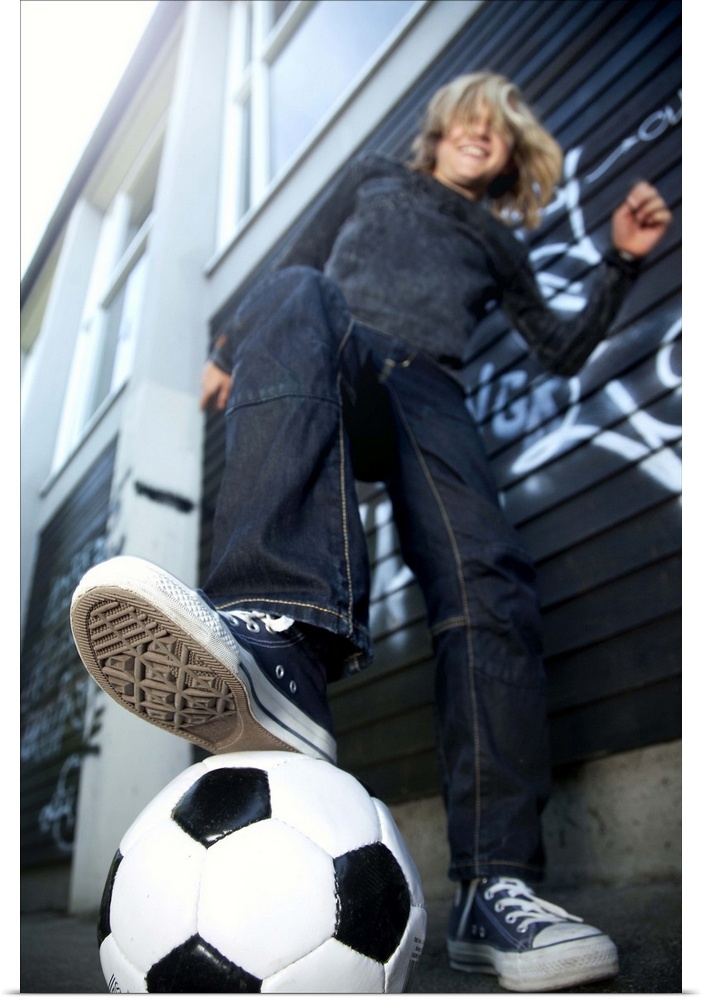 Low angle portrait view  of blond boy with football.