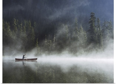Man canoeing on lake cover with fog, side view