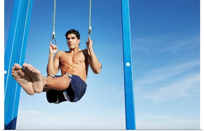 Man on a beach working out on exercise rings apparatus