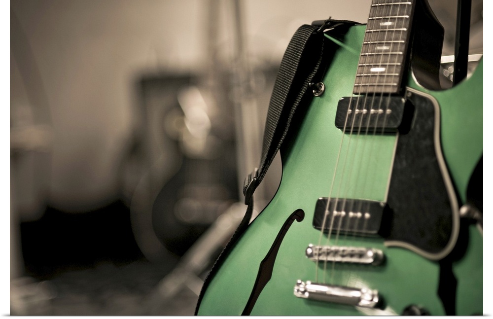 Metallic green hollow-body electric guitar used by band Neon love life. Guitar is on stand with strap. Was shot with shall...
