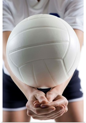 Mid section view of a young woman serving a volleyball