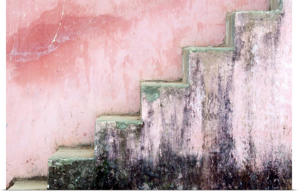 Mildewed stairs along a pink pastel colored wall at Thien Nu Pagoda in Hue in the late afternoon.