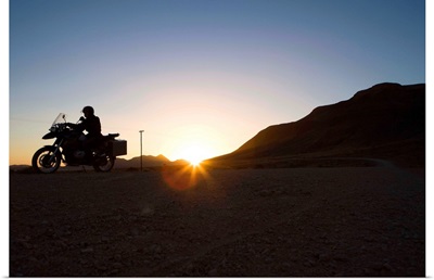 Motorcyclist riding at sunset