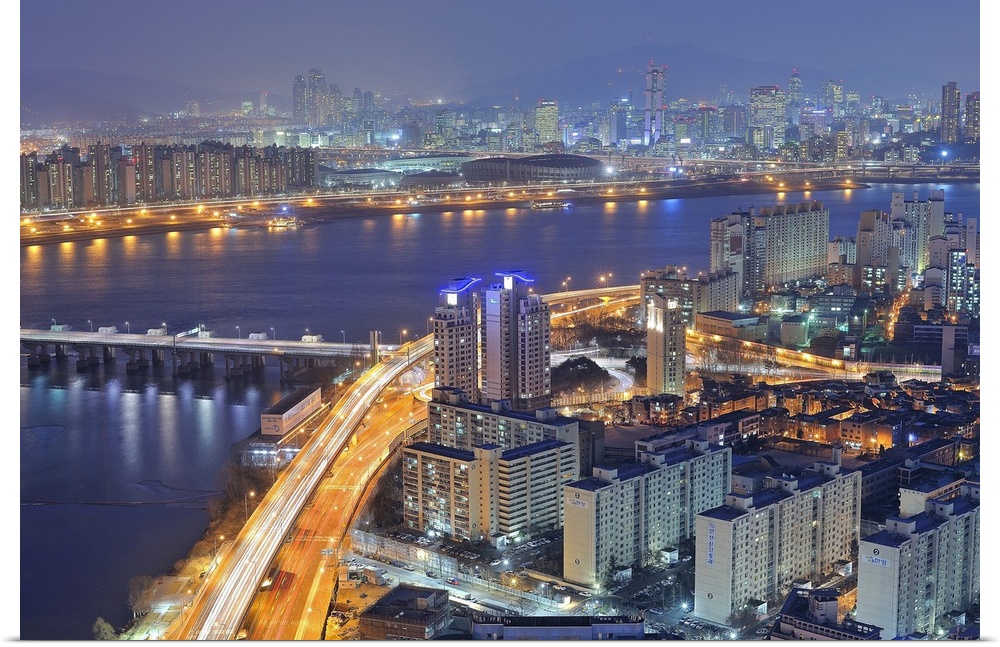 Big canvas photo of a city in Korea lit up at night along the water.