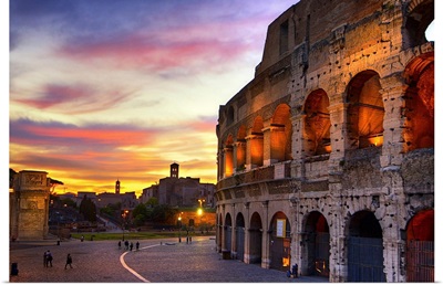 Non-traditional composition of Colosseum back lit with colors of setting sky.