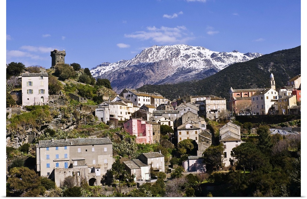 Nonza village (Corsica, France) with its famous tower in the foreground. In the background, the majestic, snow-covered mou...