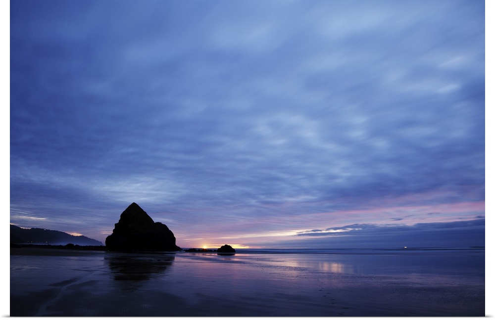 Pacific ocean, Cannon Beach, OR after the sunset. Small yellow light on the horizon is a lighthouse light.