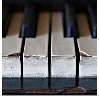 Old, antique upright piano keys displaying wear and tear.