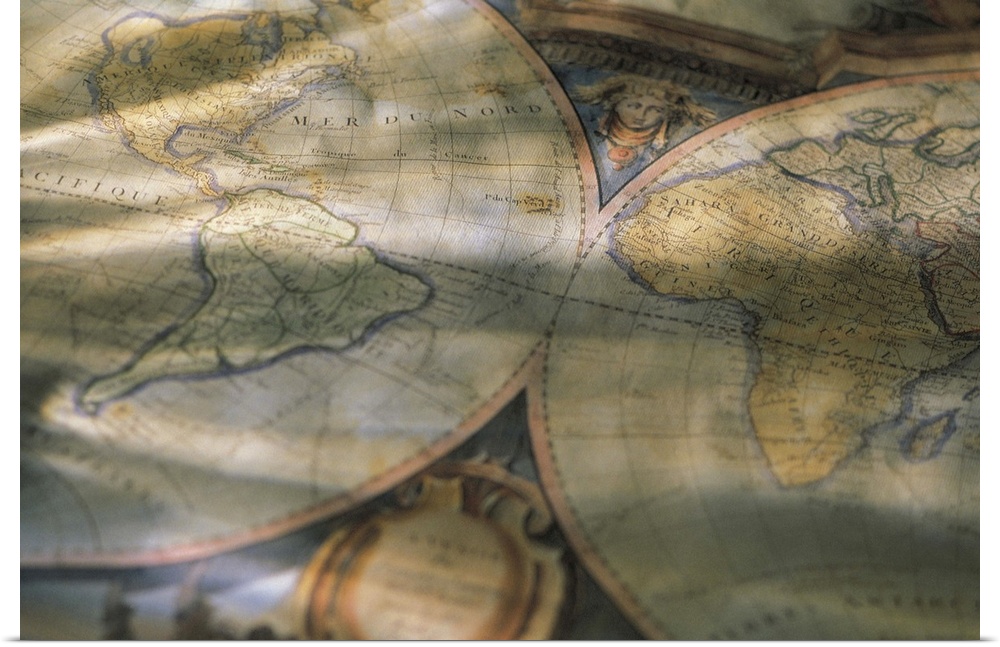 A picture is taken of an antique map of the world that is partially crinkled and sitting in a shaded room.