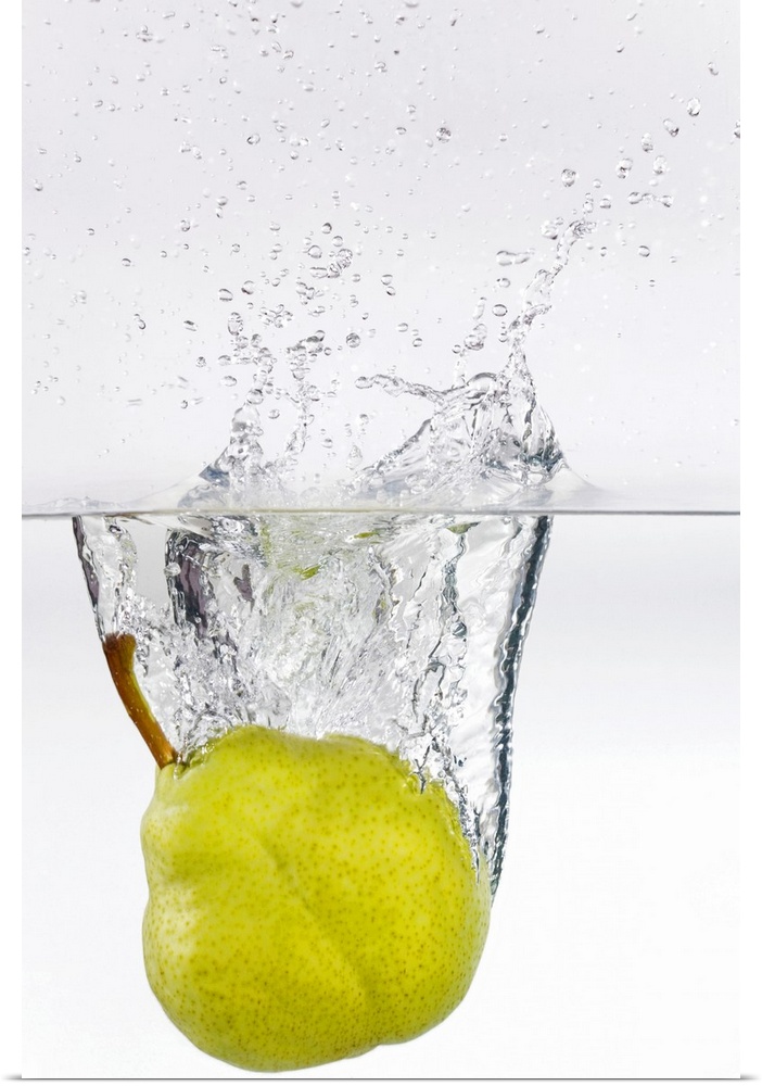 Action photography shot of a ripe pear splashing in to crystal clear water.