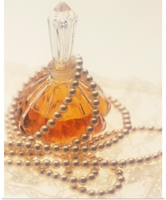 Pearl necklace draped around a perfume bottle