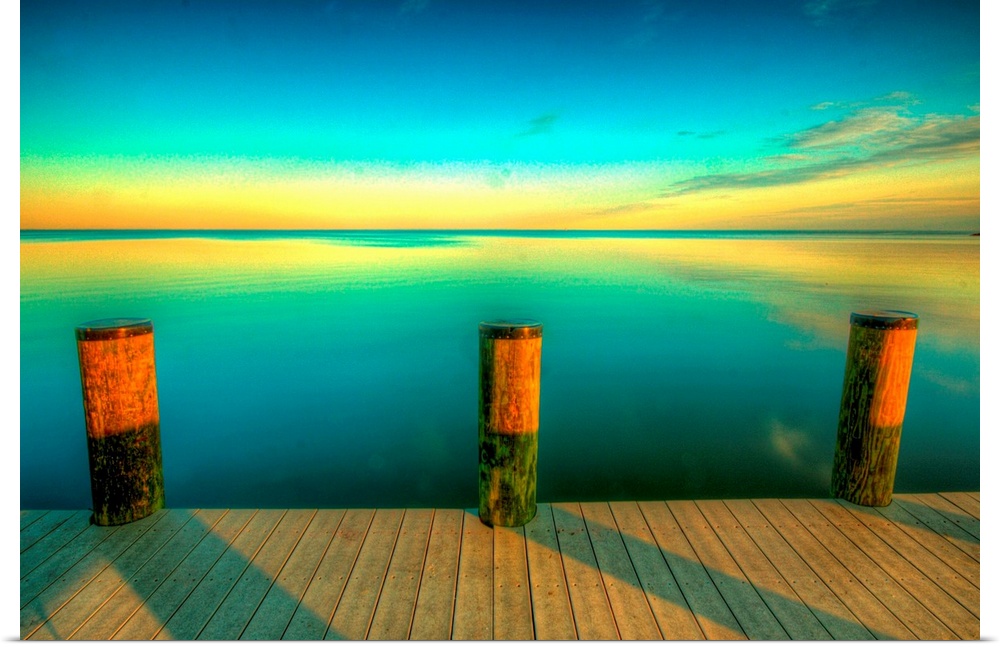 Big canvas photo art of a dock looking off onto calm water at sunset with the sky colors reflecting off of the water.