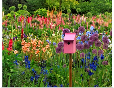 Pink birdhouse in flower garden