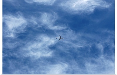 Plane in cloud filled blue sky.