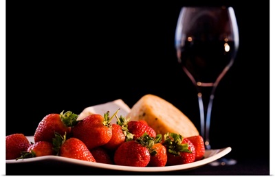 Plate of strawberries and cheeses by glass of red wine