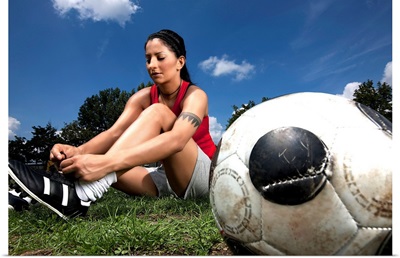 Portrait of female football player tying her shoes