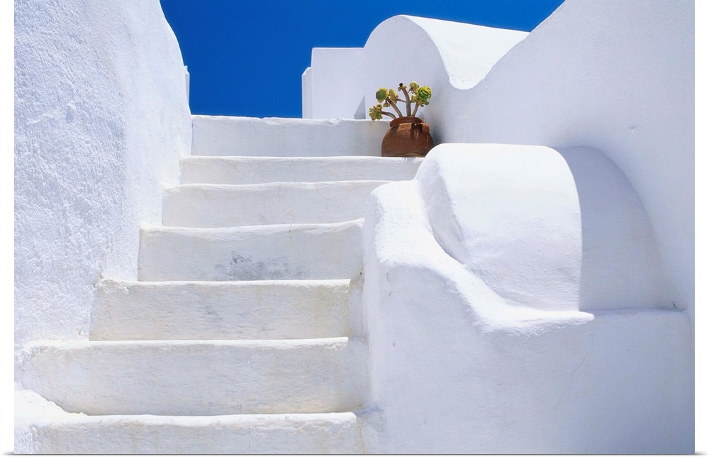 Potted flowers at the top of a white staircase on Santorini Island in Greece.