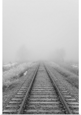 Railroad tracks fade into the morning fog