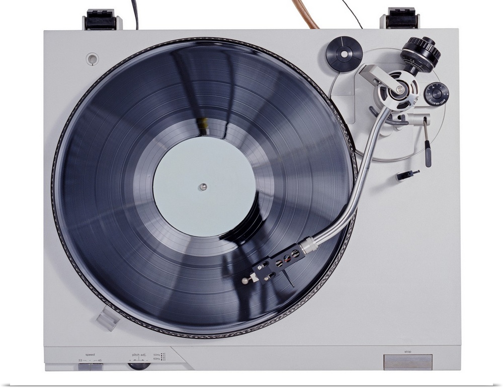 This photograph is taken of a vintage record player looking down at the record as it plays on the turn table.