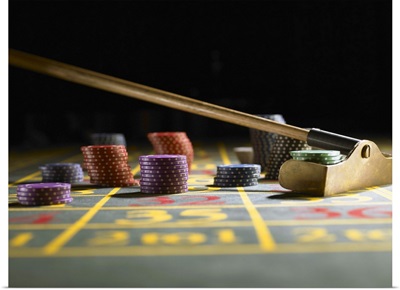 Roulette rake gathering gambling chips on gaming table