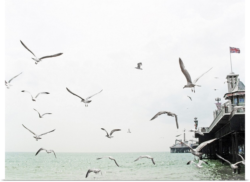 Seagulls flying around Brighton pier with Union Jack mast.