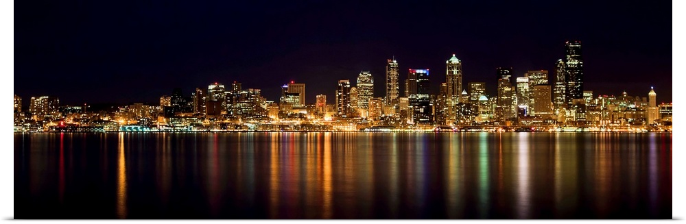 Nighttime shot of downtown Seattle at night with lights of city reflected in water of Puget Sound.