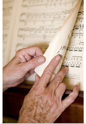Senior's hands turning page of sheet music