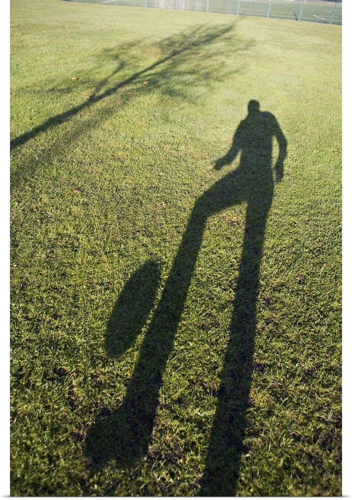 Shadow of man kicking soccer ball in the air