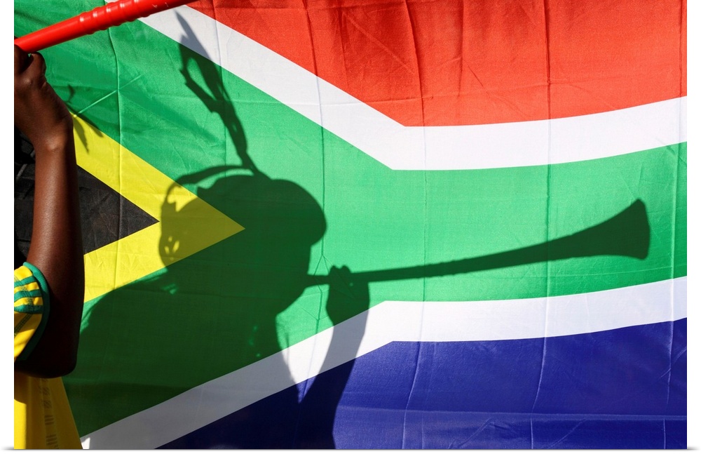 Shadow of soccer supporter blowing vuvuzela, South African flag in background, Johannesburg, South Africa