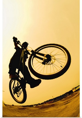 Silhouette of a cyclist against a yellow sky