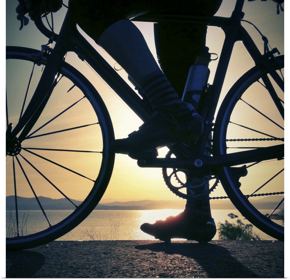 A cyclist pauses with his road bike to watch the sun rise over Folsom Lake, in Folsom, California, on a warm spring morning.