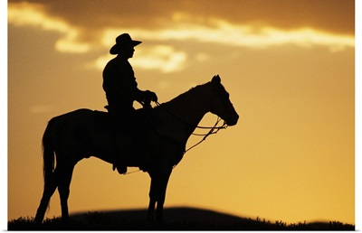 Silhouette of cowboy on horseback at sunset or sunrise