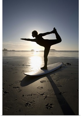silhouette of female surfer doing bow pulling yoga pose