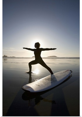 silhouette of female surfer doing warrior yoga pose