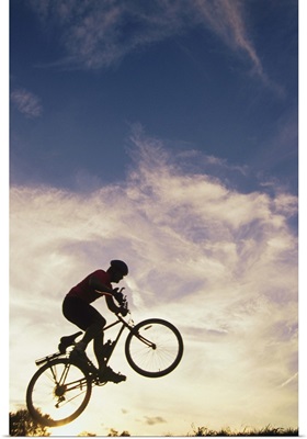 Silhouette of man in mid-air on mountain bike