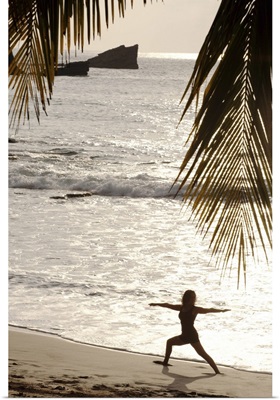 Silhouette of woman doing yoga on beach