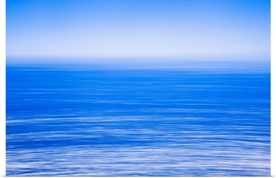 Silky calm blue open sea with fog or mist over water, Blue sky