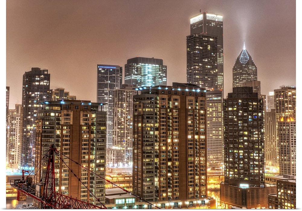 A photograph taken of the Chicago skyline at night with the buildings illuminated and snow beginning to fall on the city.