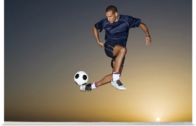 Soccer player kicking ball in mid air