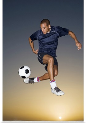 Soccer player kicking ball in mid-air