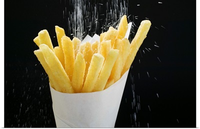 Sprinkling salt on fries in paper cone