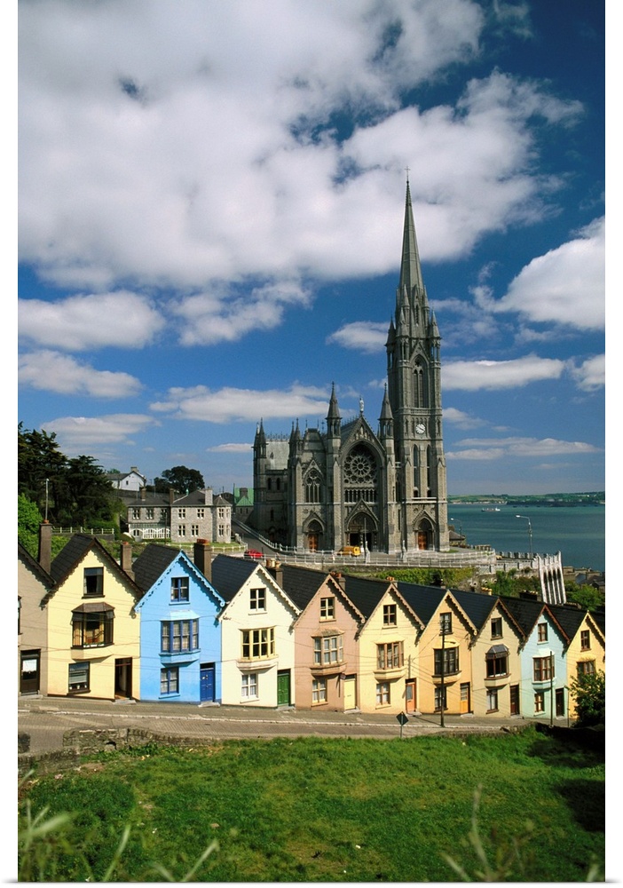 St. Coleman's Cathedral towers over multicolored row houses in the town of Cobh, in Cork County, Ireland. Cork Harbor is v...