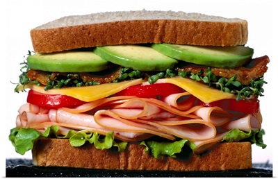 Stacked turkey sandwich with avocados, cheese, tomatoes and crunchy lettuce